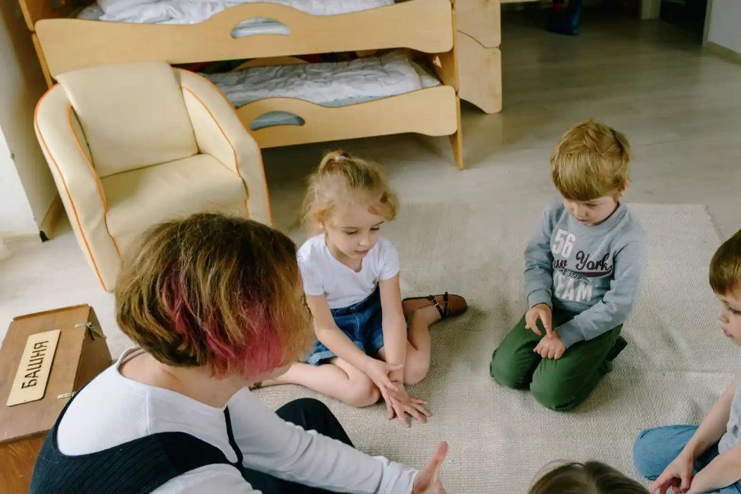 Pedagog sitter på golvet med en grupp förskolebarn